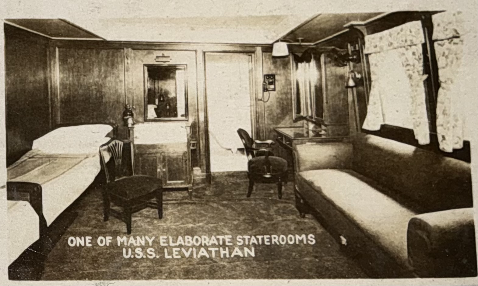 Passenger stateroom furnished with bed, sofa and writing desk.