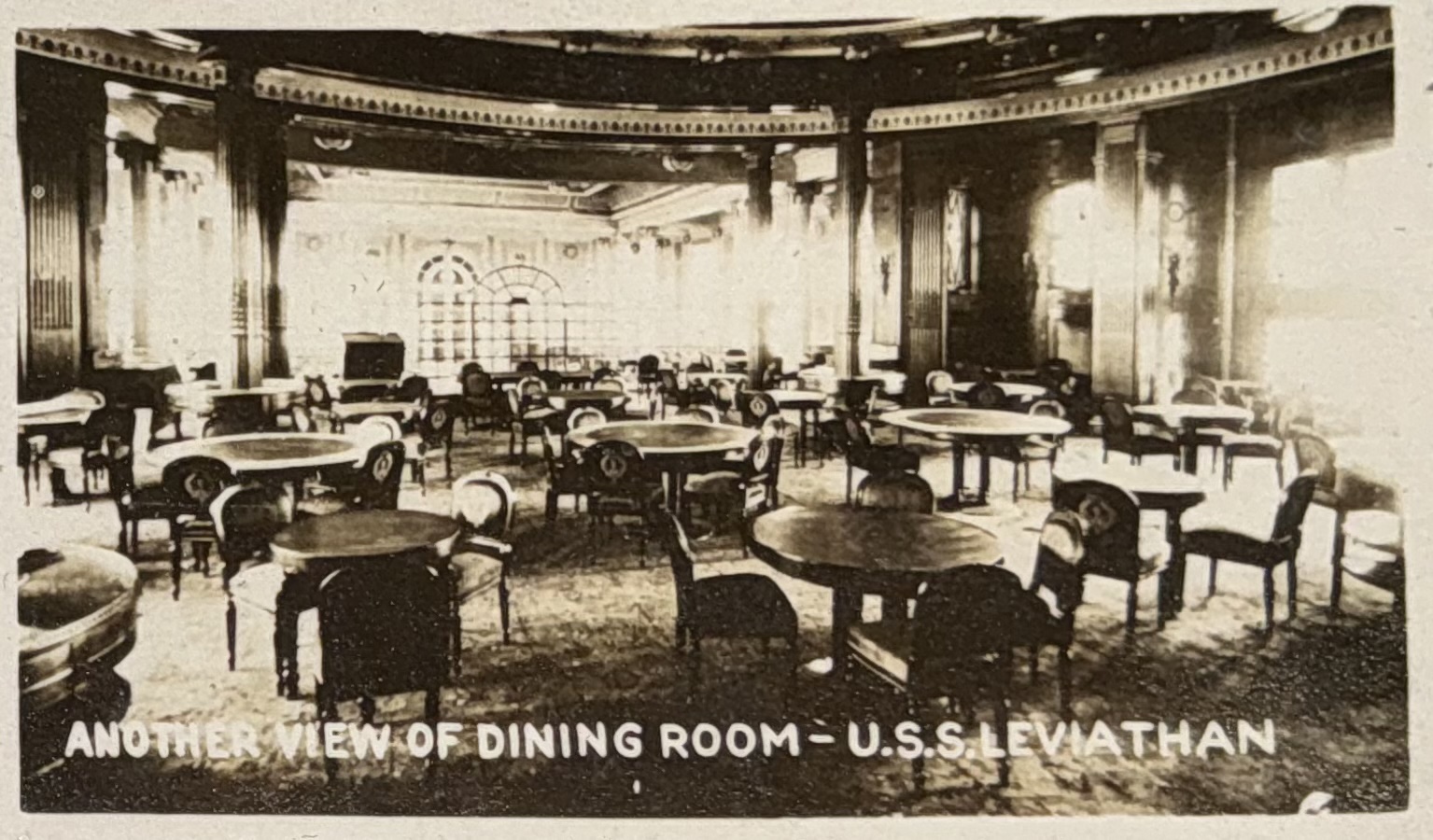 Another view of the dining room with round tables and ornate architectural details.
