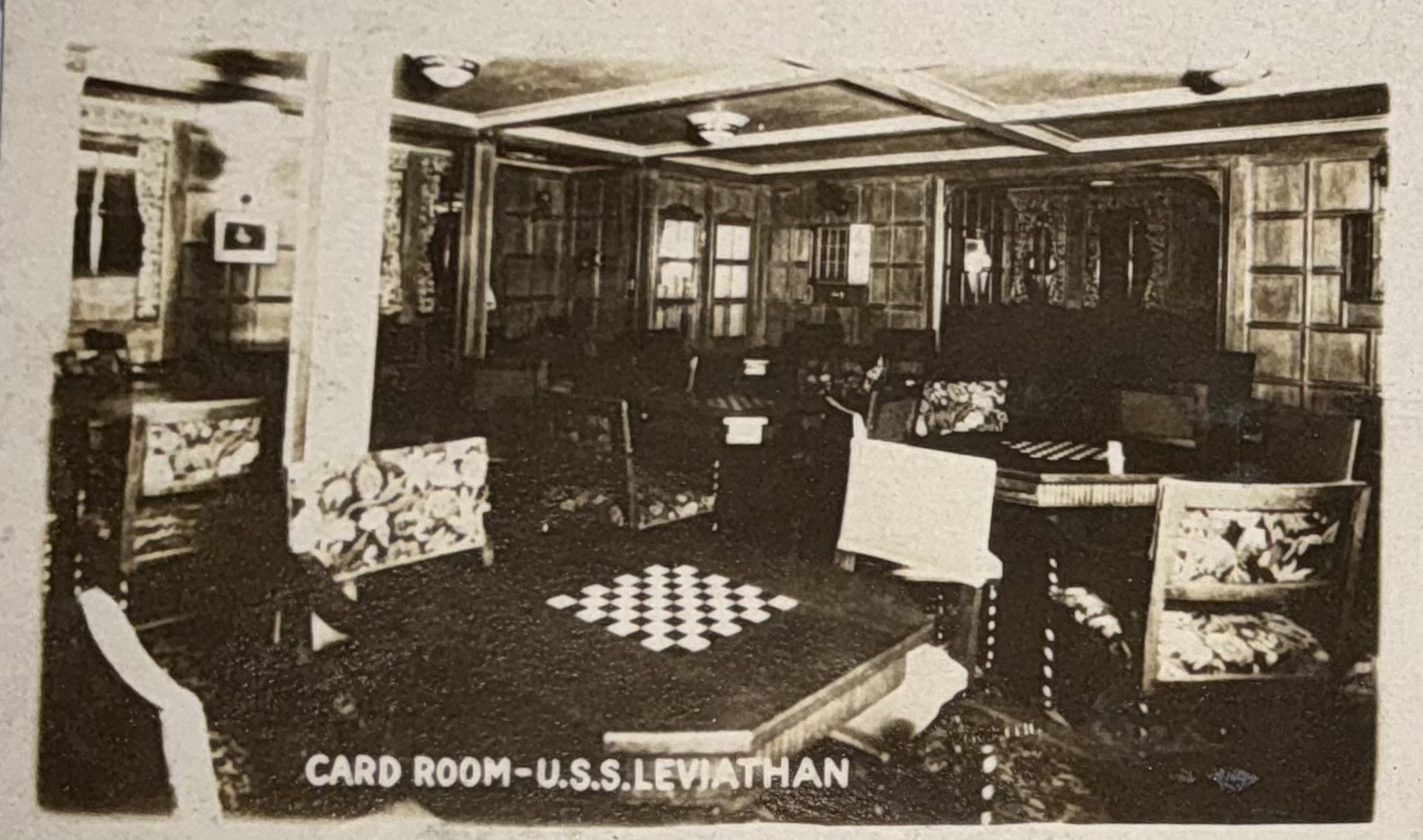 Wood-paneled card room with tables and upholstered chairs.