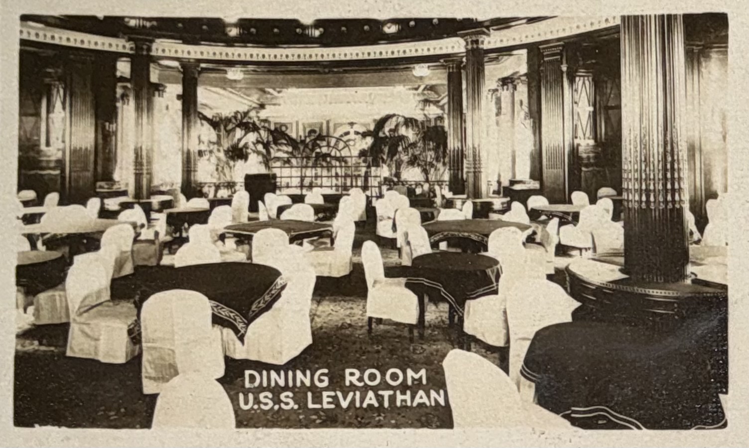 Dining room with tables and white-covered seating.