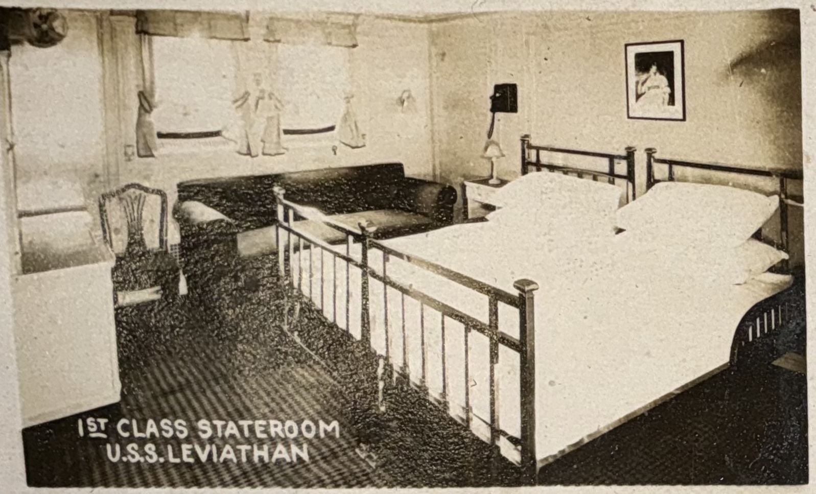 First-class stateroom with twin beds and seating area.