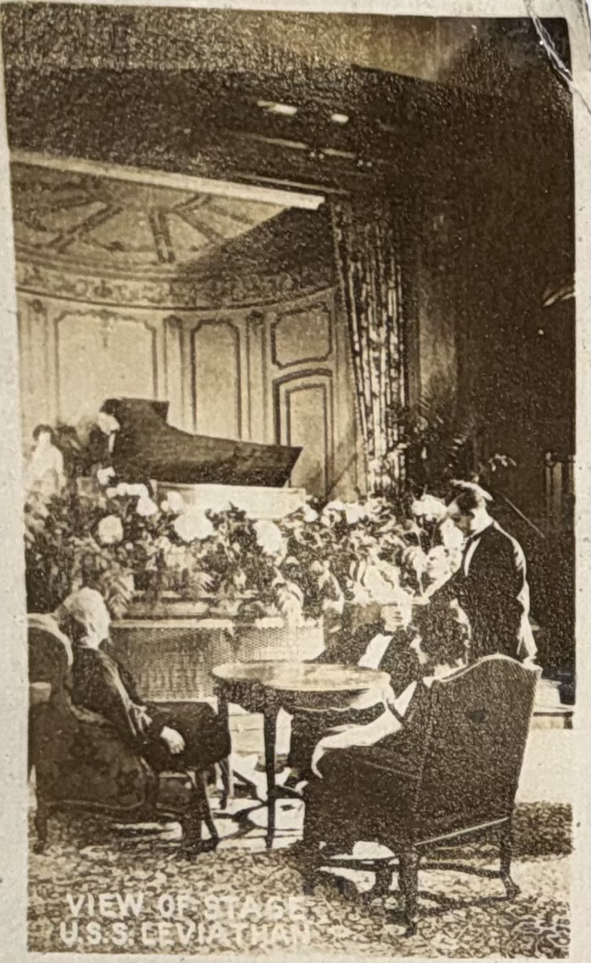 Passengers gathered in a lounge with piano and flowers.