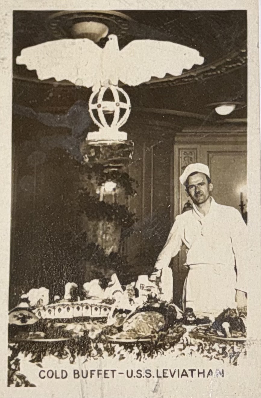 Crew member beside a cold buffet and decorated platters.